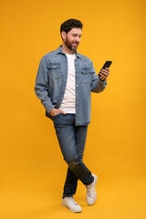 Smiling man with smartphone on orange background