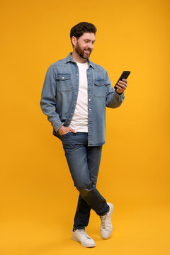 Smiling man with smartphone on orange background