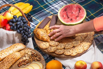 View of different food for summer picnic on checkered blanket, closeup with selective focus. The concept of summer outdoor recreation on the weekend