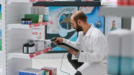 Pharmaceutical helper monitors the medication stock on shelves, scanning boxes that include...