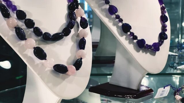 Necklaces adorned with semi-precious gemstones (Amethyst, Tanzanite, Sapphire, and Iolite) displayed in a jeweler's shop window