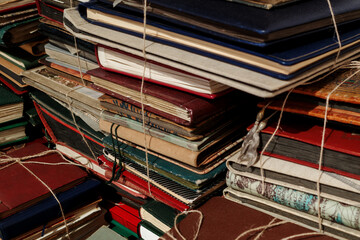 A collection of old and worn books bound with twine, stacked in a haphazard fashion. 