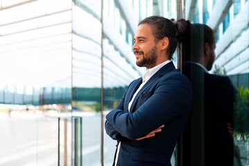 Confidence successful businessman in suit with beard standing in front of office glass building...