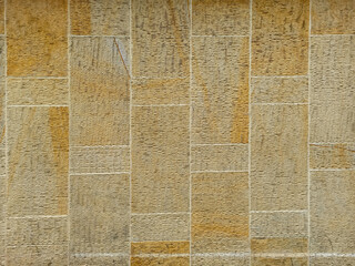 Fototapeta premium Background texture of a beige sandstone block wall with a grid pattern.