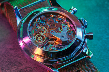 Close up detail of a macro clockwork inside a shiny iron wristwatch with sapphire rear glass bottom. - 774498324