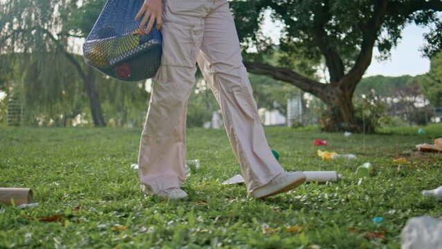 Volunteer walking park trash pollution. Conservationist girl stepping grass