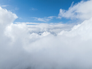 Aerial view of dense, white clouds covering Verbier, Switzerland, with a clear blue sky above,...