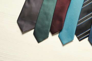 Different neckties on white wooden table, flat lay. Space for text