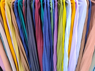 collection of colorful Vibrant fabric of clothes hanging on clothes hanger in closet or clothing rack. background of colorful clothes
