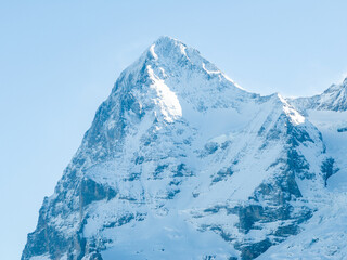 A majestic, snow covered mountain peak in the Swiss Alps near Murren basks in soft sunlight. Its...