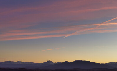 Fototapeta na wymiar Tramonto luminoso rosso e azzurro nello spazio immenso del cielo sopra la catena dei monti Appennini