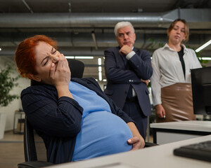 Pregnant woman yawns at work. Colleagues look disapprovingly. 