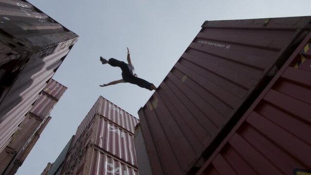 Parkour man jumping over shipping containers - Low shot
