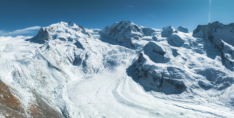 Aerial view near Zermatt, Switzerland, showcasing snow covered alpine peaks under a clear blue sky....