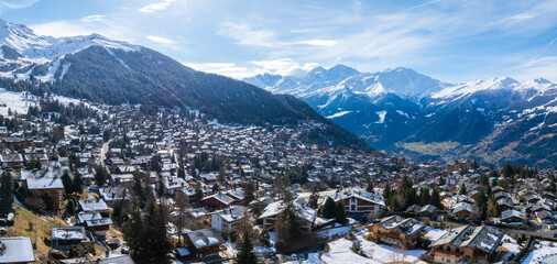 Aerial shot of Verbier, a Swiss Alps ski town, displays chalets in a snowy setting. It shifts...