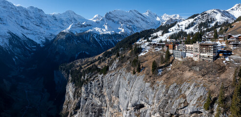 Aerial view of Murren, Switzerland, perched on a cliff with snow capped Swiss Alps in the...