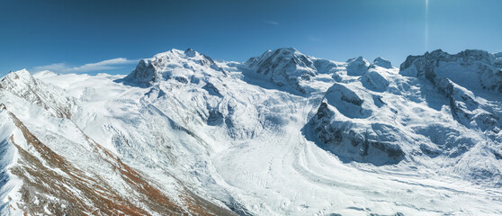 A stunning view of Zermatt ski resort in Switzerland shows rugged, snow capped peaks under a clear...