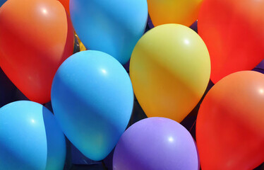 A bunch of colorful balloons, including red, yellow, and pink, float playfully in a bright blue sky, perfect for a festive celebration