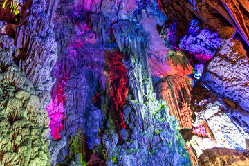 Illuminated multicolored stalactites, Reed Flute cave. Guilin Guangxi. China