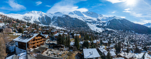 Panoramic aerial view of Verbier, Switzerland, displays chalets in a valley against snow capped...
