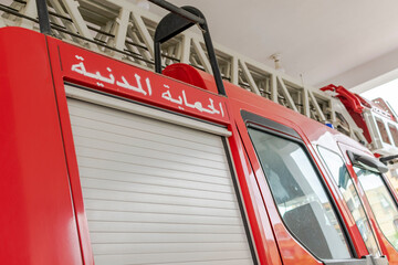 Lateral side of a fire truck parked outdoors in a fire station, red colored with a ladder on the...
