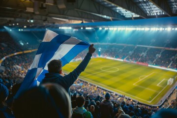A man holding a blue and white flag in a stadium full of people. Football fan supporting the team
