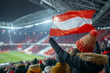 A woman is holding a red and white flag in a stadium full of people. Football fans at the football championship
