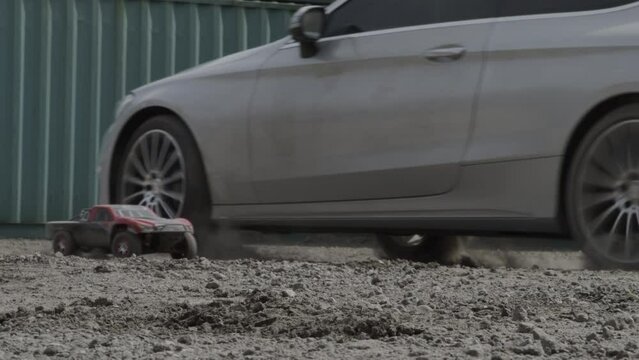 Vehicle and RC car kicking up dirt in cinematic slow motion