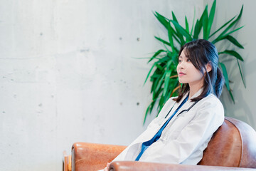 白衣で休憩をする女性の医師