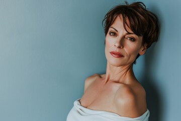 portrait of beautiful mature woman with bare shoulders looking at camera isolated on grey