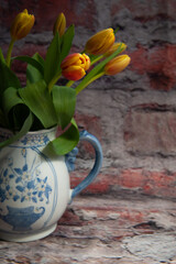bouquet of red and yellow tulips in a blue pitcher