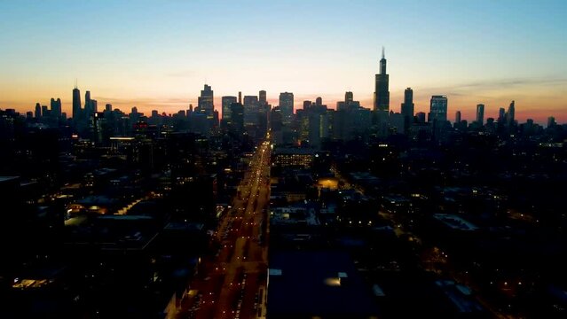 A captivating drone aerial view of a Chicago at dusk, showcasing illuminated skyscrapers against the darkening sky The golden hues of sunset paint a serene backdrop, highlighting architectural marvels