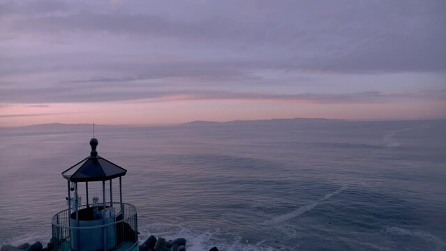 Santa Cruz Harbor lighthouse sunrise. Drone revealing lighthouse and then rising in altitude to reveal bigger scene.