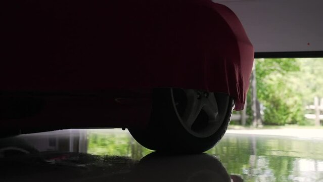 Electric Garage door opening revealing a red covered Sports Car