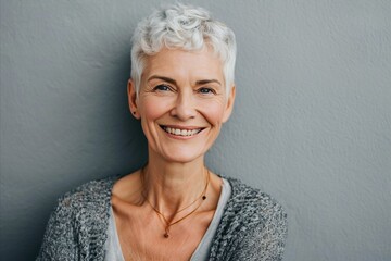 Close up portrait of a smiling senior woman standing against grey background.