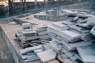 Piles of granite tiles ready for installation at a new building site at dawn.