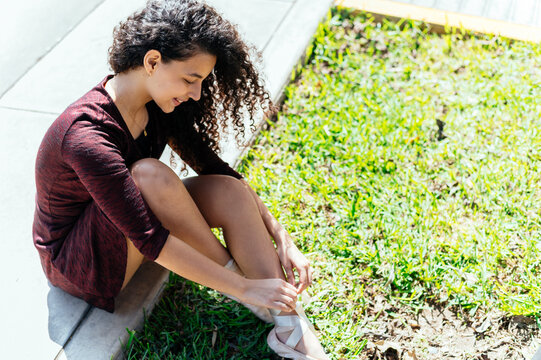 Young dancer tying ballet shoes outdoors - Powered by Adobe
