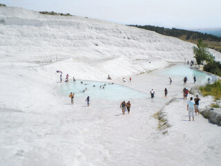 Tourists bathe in Pamukkale thermal springs with cascading terraced baths decorated with snow white calcite stalactites in Denizli province, southwestern Turkey.