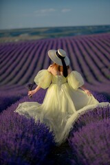 Back view woman lavender sunset. Happy woman in yellow dress holds lavender bouquet. Aromatherapy concept, lavender oil, photo session in lavender