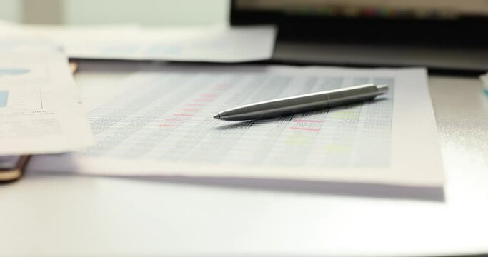 Analyzing financial data and graphs with pen on table