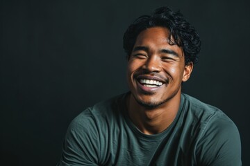 Portrait of a happy young asian man laughing against black background