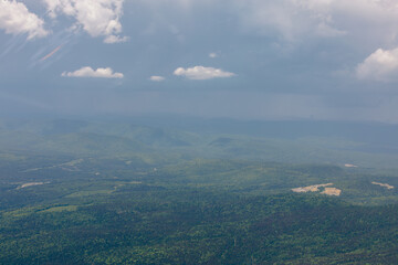 vue en hauteur d'un terrain sauvage avec des arbres verts et des nuages de tempête dans le ciel lors d'une journée d'été