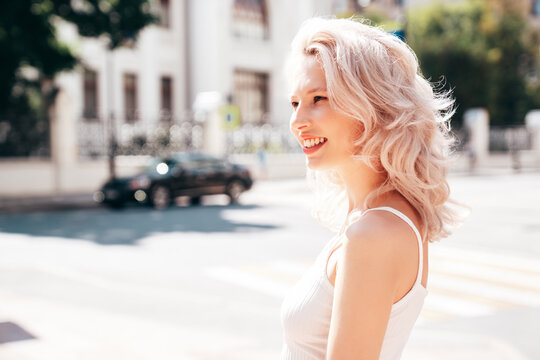 Closeup portrait of young beautiful smiling woman. Sexy carefree model posing on the street background at sunset. Positive blond female. Cheerful and happy. Outdoors at sunny day
