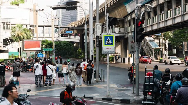 Traffic of Asok intersection in Bangkok, Thailand in timelapse. Thai text on road sign means stop for pedestrian in crosswalk.