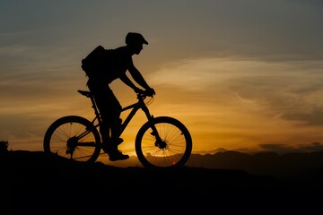 Obraz premium shot Silhouette of a man on mountain bike at sunset photo