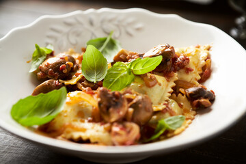 Ravioli with mushrooms and fresh basil. Dark wooden background. Close up	