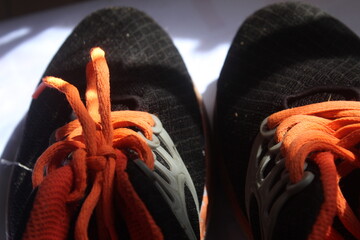 Cut out black sports shoes with orange laces. suitable for background and texture themes