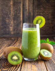 Green kiwi juice on wooden background. Healthy drink in a glass, diet, summer drink.