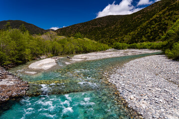 Fast flowing clear river running through a forest and mountains