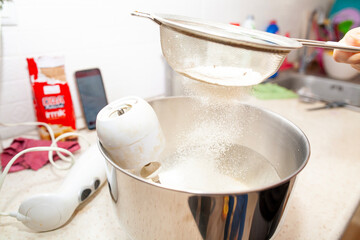 Sprinkling flour into the mixing bowl with a strainer for making cakes